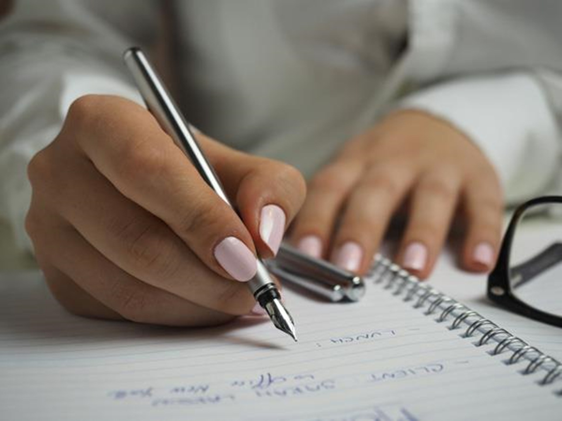 Hand hält Füller in der Hand und schreibt etwas auf Papier
