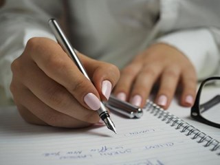 Hand hält Füller in der Hand und schreibt etwas auf Papier