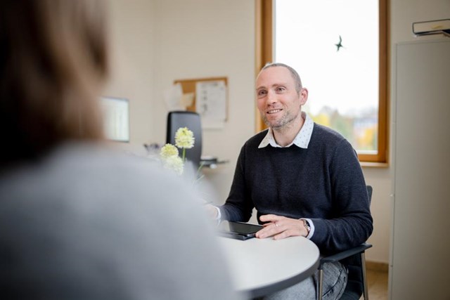 Ein Mann sitzt an einem Tisch und macht sich Notizen zu einem Gespräch