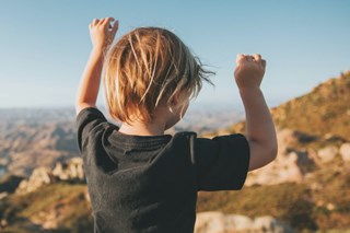 Ein kleiner Junge hebt die Arme nach oben