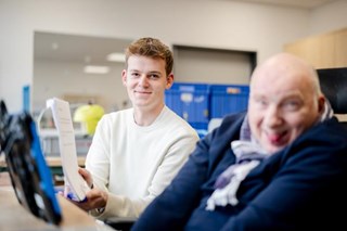 Junger Mann und Mensch im Rollstuhl nebeneinander