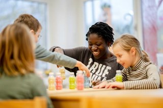 Junge Frau spielt mit Kindern am Tisch