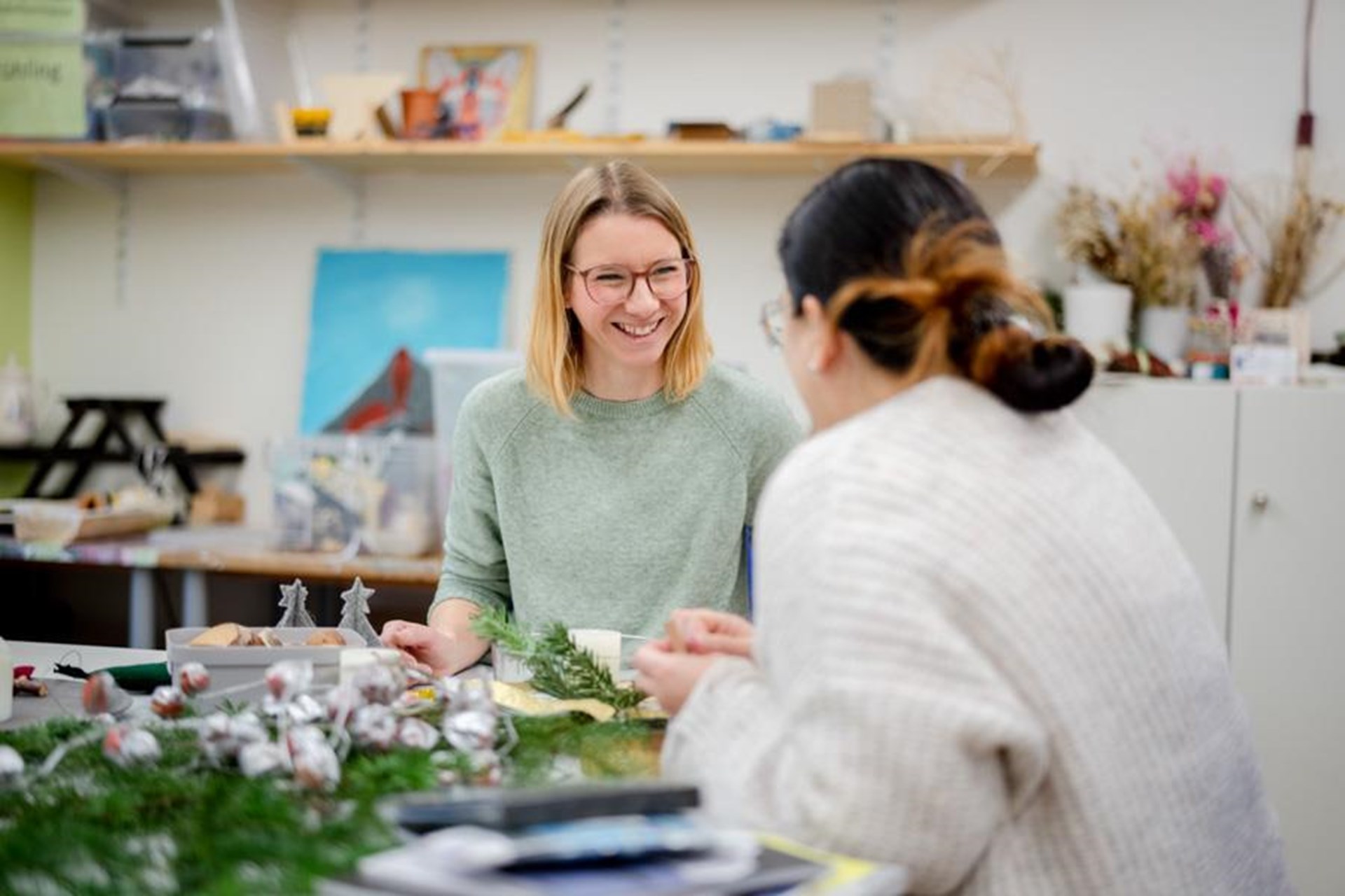 zwei Frauen sitzen an einem Tisch und basteln