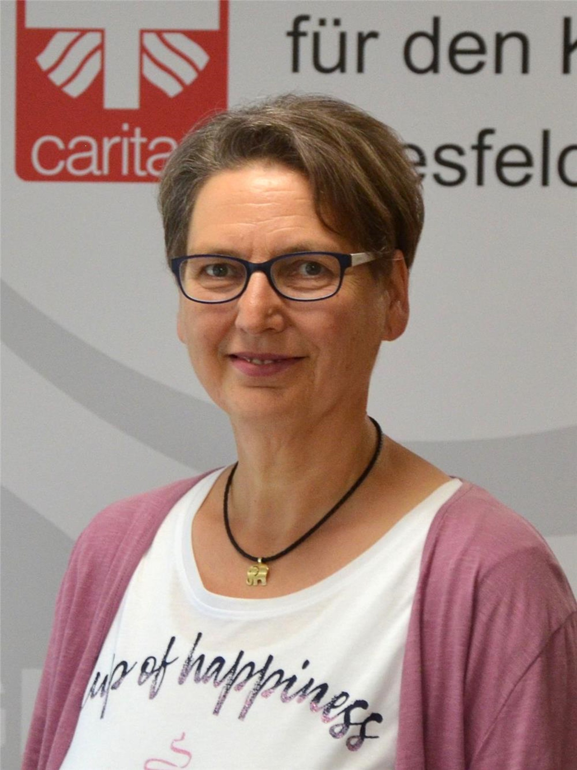 Portraitfoto von Gabriele Schlotmann mit Caritas-Logo im Hintergrund